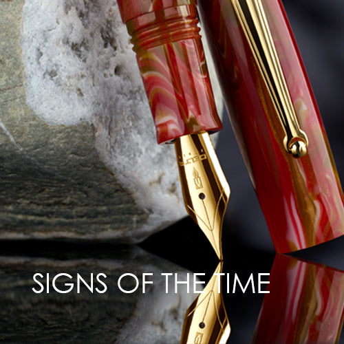 Marbled red and gold pen with gold clip on a reflective surface, 'SIGNS OF THE TIME' text overlay.
